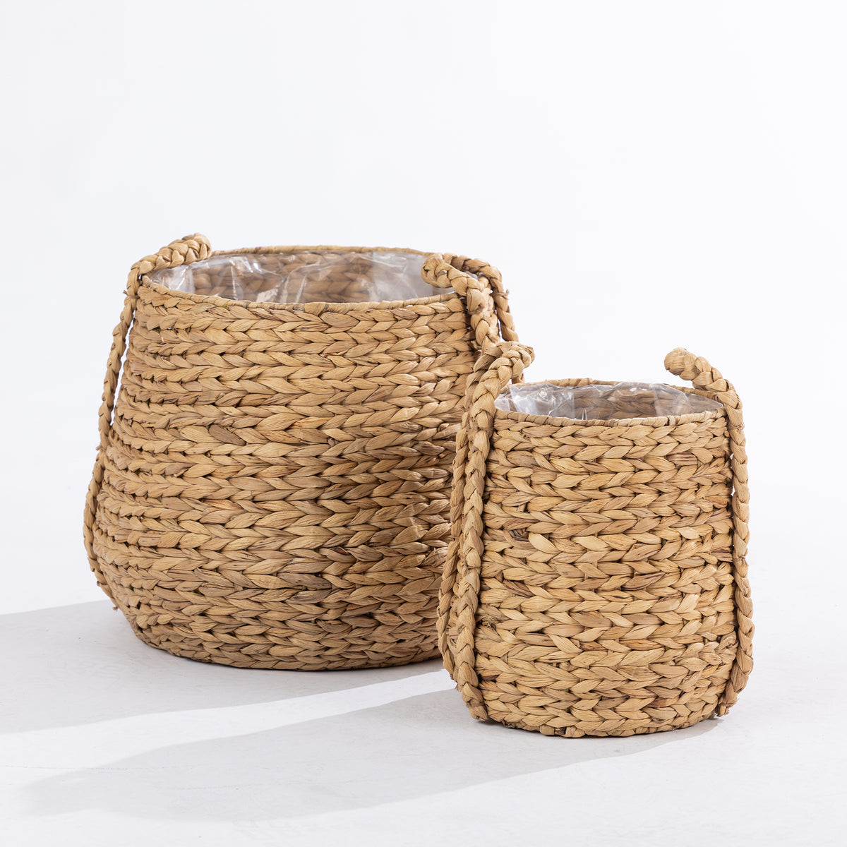 Two natural woven baskets in large and small sizes with braided handles and clear inner liners, shown together against a white background.
