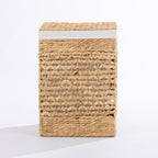 Natural woven laundry hamper with a decorative open weave design, matching lid and white fabric trim, shown closed against a white background.