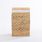 Natural woven laundry hamper with a decorative open weave design, matching lid and white fabric trim, shown closed against a white background.
