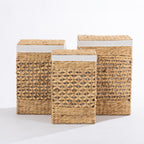 Three natural woven laundry hampers in small, medium and large sizes with matching lids and white fabric trim, displayed together against a white background.