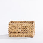 Natural woven rectangular storage basket with an open decorative weave, shown at a slight angle against a white background.