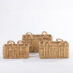 Three natural woven rectangular baskets with braided handles, arranged together against a white background.