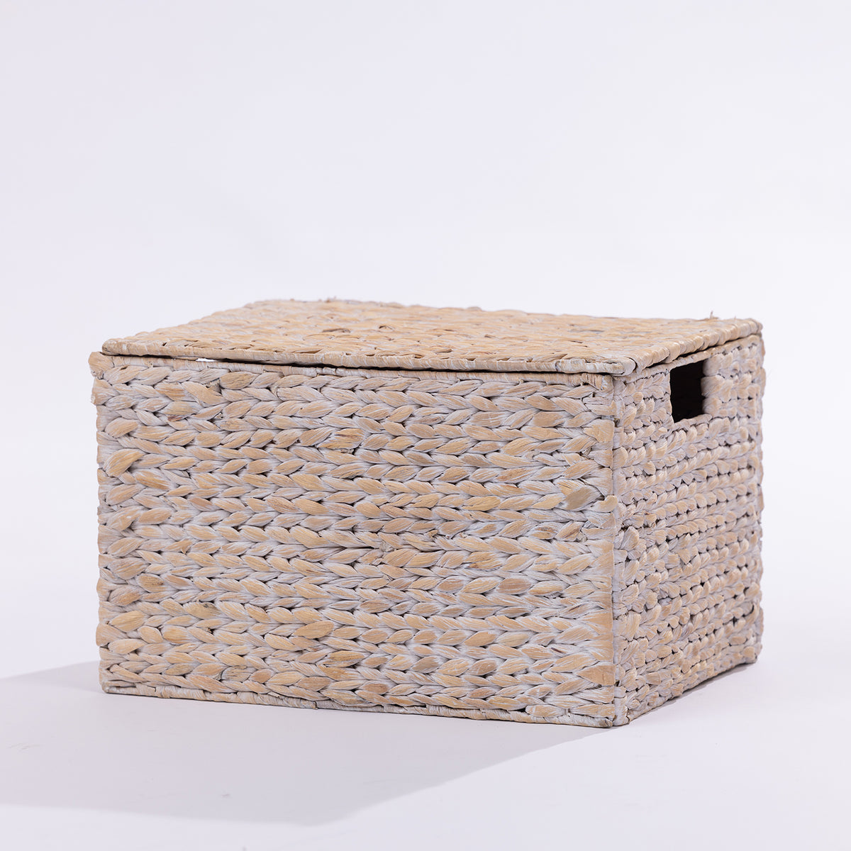 A rectangular woven storage box with a lid, made from natural jute or seagrass fibers, featuring a small cutout handle on the side, photographed on a clean white background.