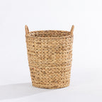 A natural woven straw basket with two loop handles, photographed on a clean white studio background.