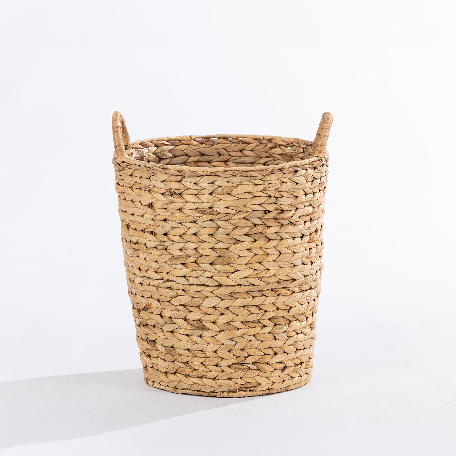 A natural woven straw basket with two loop handles, photographed on a clean white studio background.
