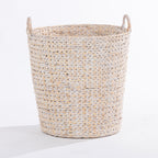 A natural woven basket made from or straw, featuring two loop handles on the sides, photographed on a clean white studio background.