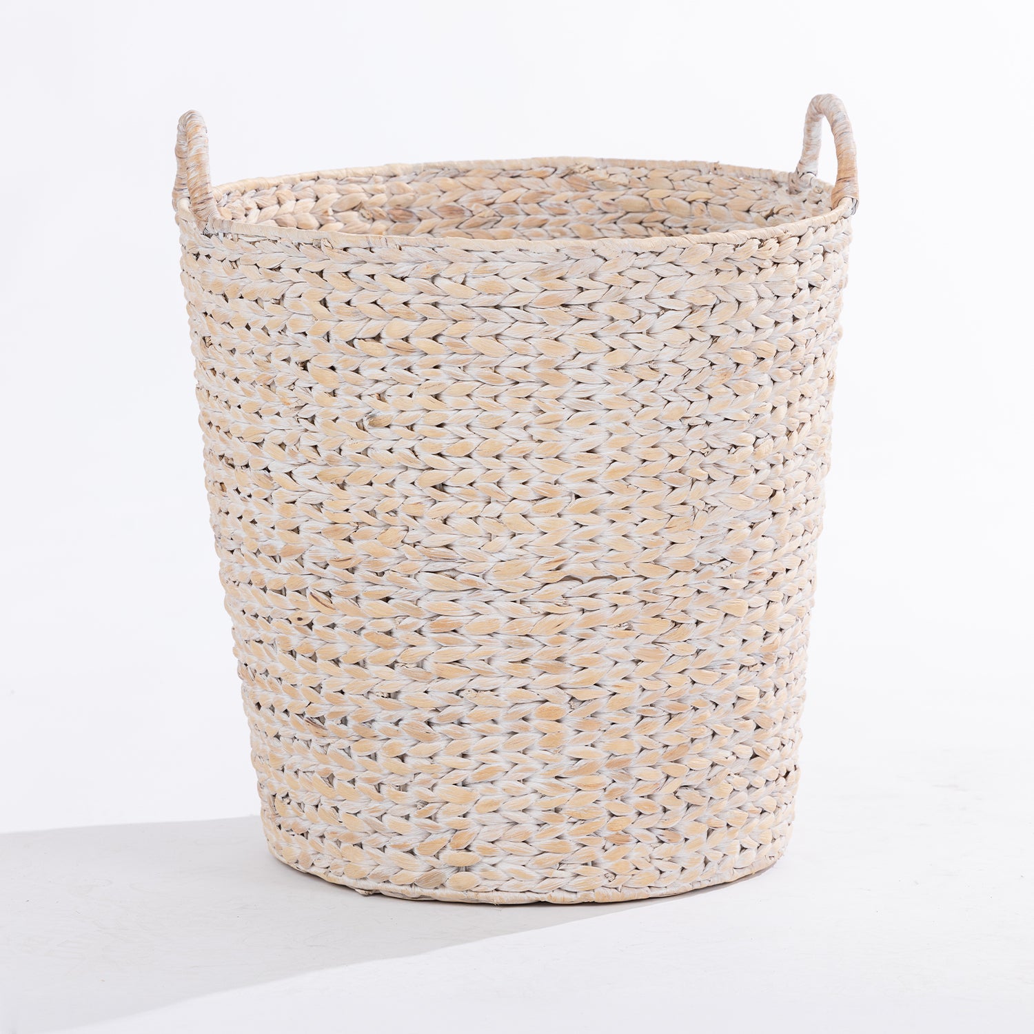 A natural woven basket made from or straw, featuring two loop handles on the sides, photographed on a clean white studio background.