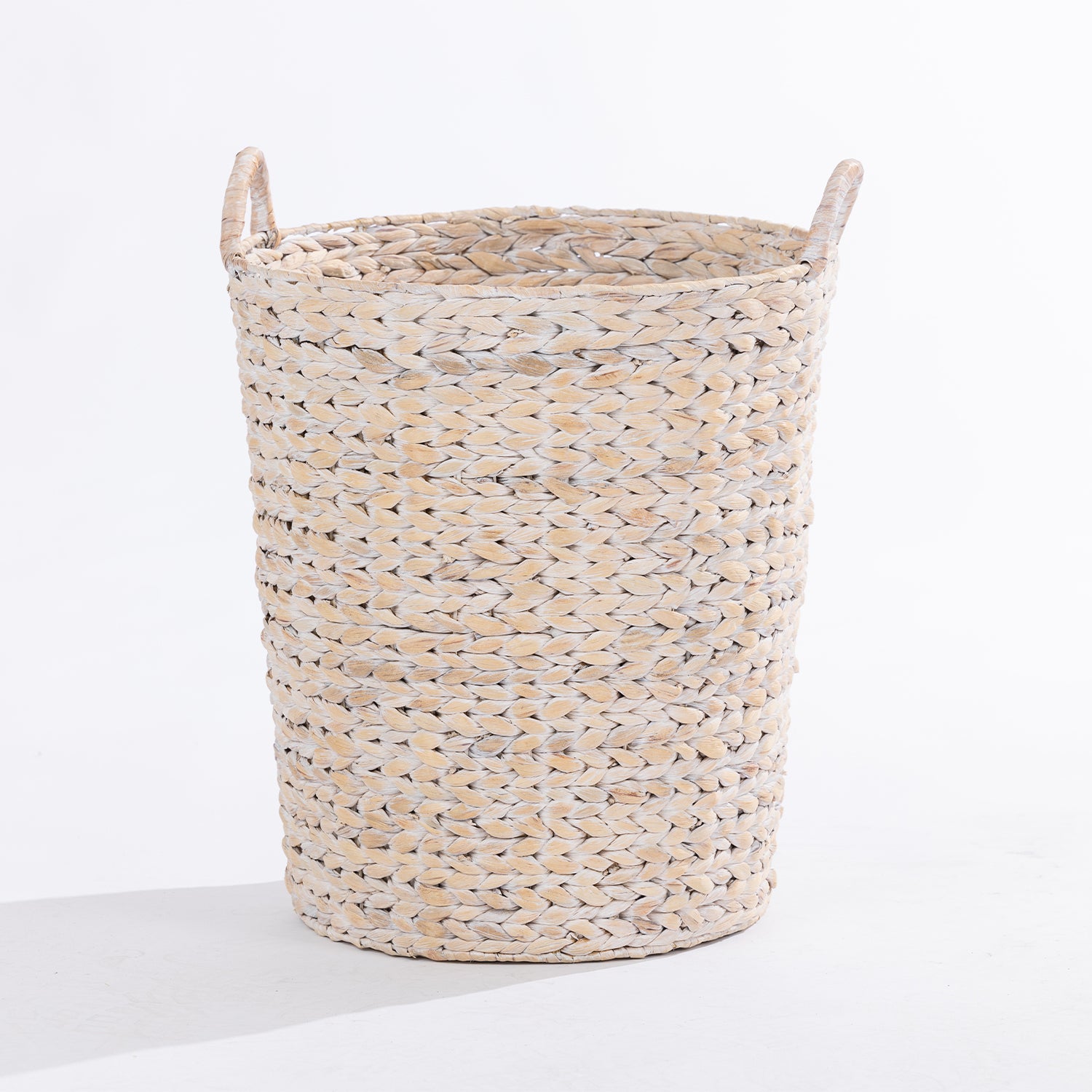 A natural woven or straw laundry basket with two loop handles, shown on a clean white background.