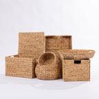 A set of natural woven storage baskets and bins in various sizes, made from seagrass or straw, arranged on a clean white studio background.