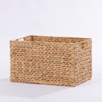 A rectangular woven storage basket made from natural seagrass or straw, featuring a braided texture and small loop handles on the sides, shown on a plain white background.