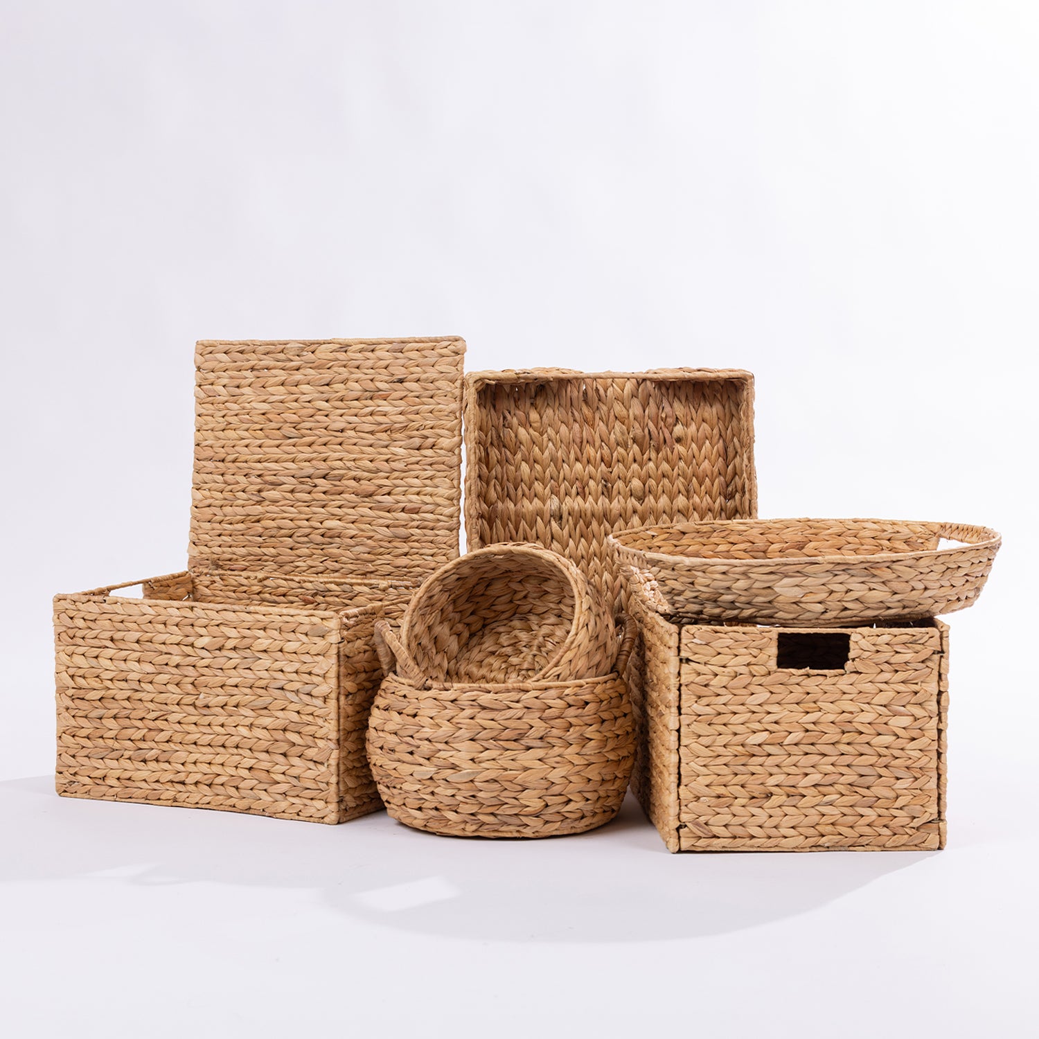 A set of natural woven storage baskets and bins in various sizes, made from seagrass or straw, arranged on a clean white studio background.