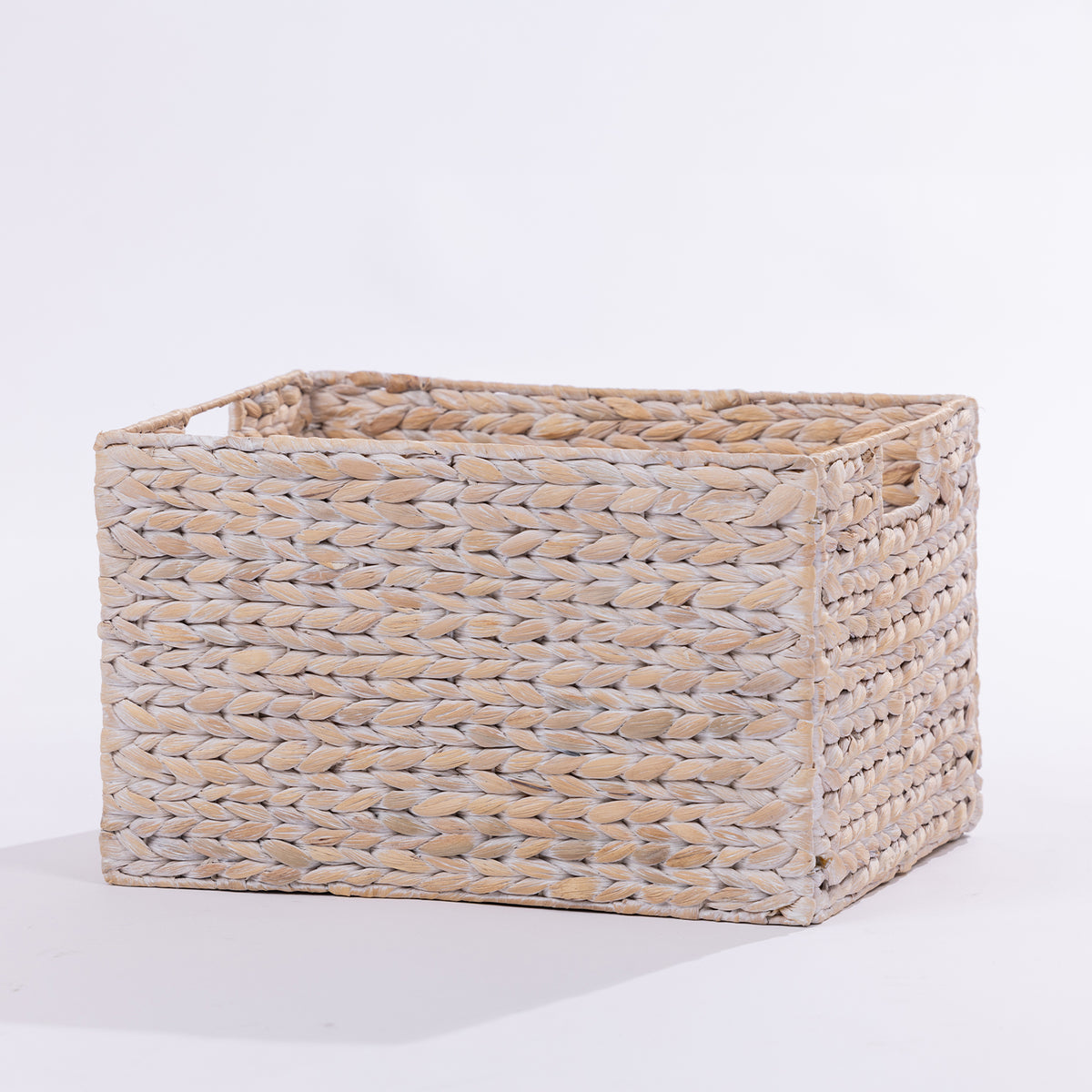 A rectangular woven storage basket made from natural seagrass or wicker, featuring integrated side handles and a slatted open top, shown on a plain white studio background.