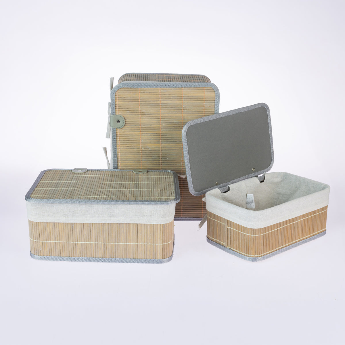 Home Co. Ashton Bamboo Storage Basket Set with Lids in Grey, featuring rectangular natural bamboo baskets with grey trim, cream fabric linings and matching lids, displayed open and closed on a white background.