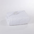Folded white electric blanket on a white surface.