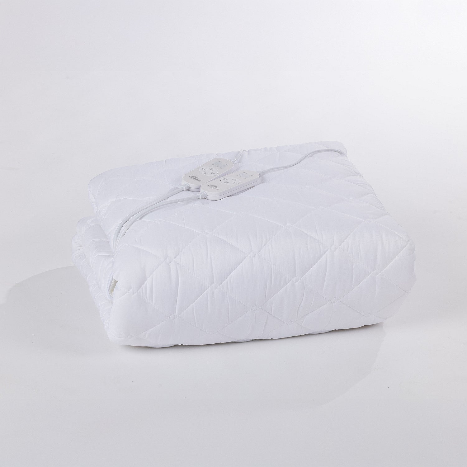 Folded white electric blanket on a white surface.