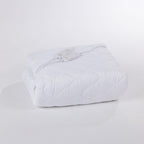 Folded white electric blanket with two sets of controllers on top with a white background