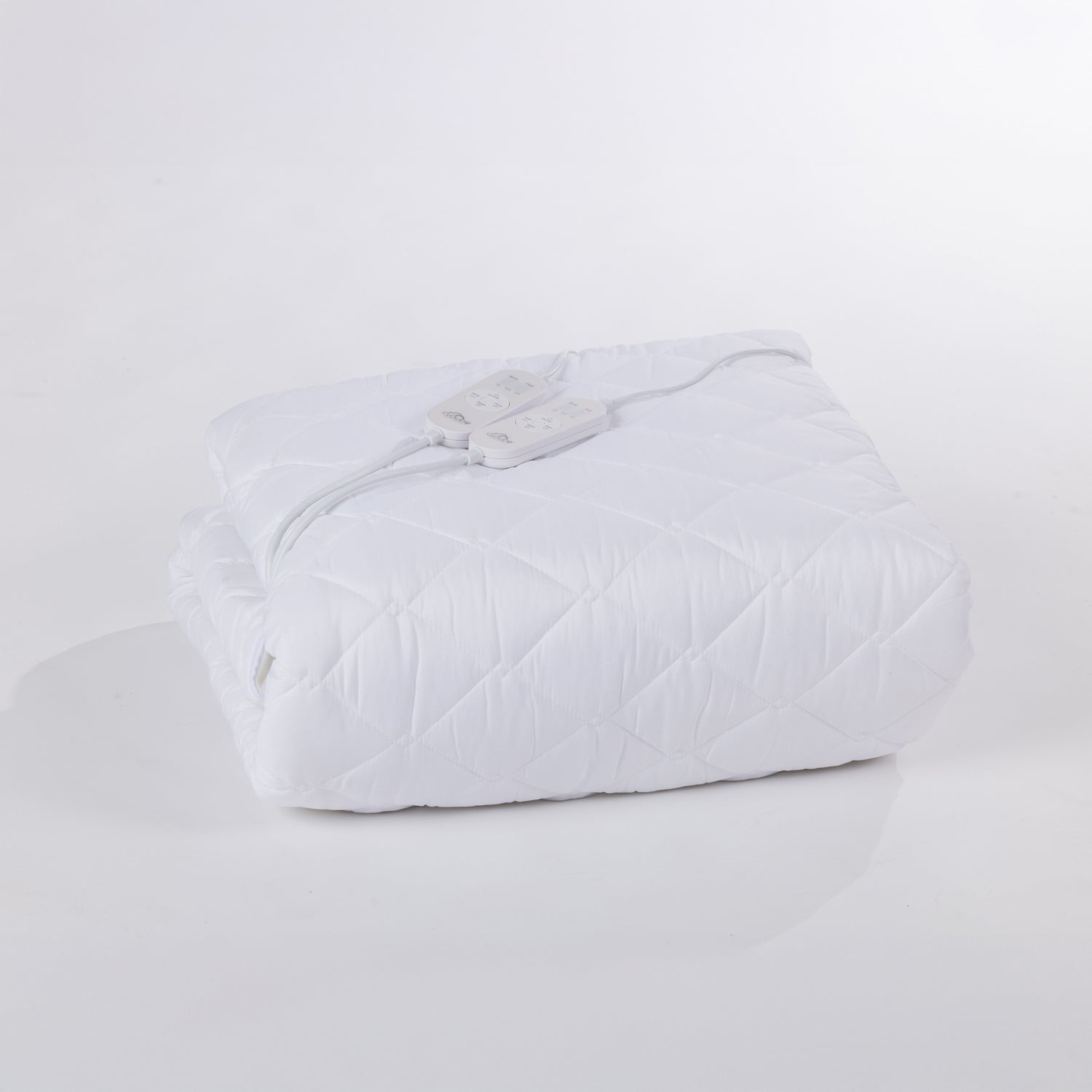Folded white electric blanket with two sets of controllers on top with a white background