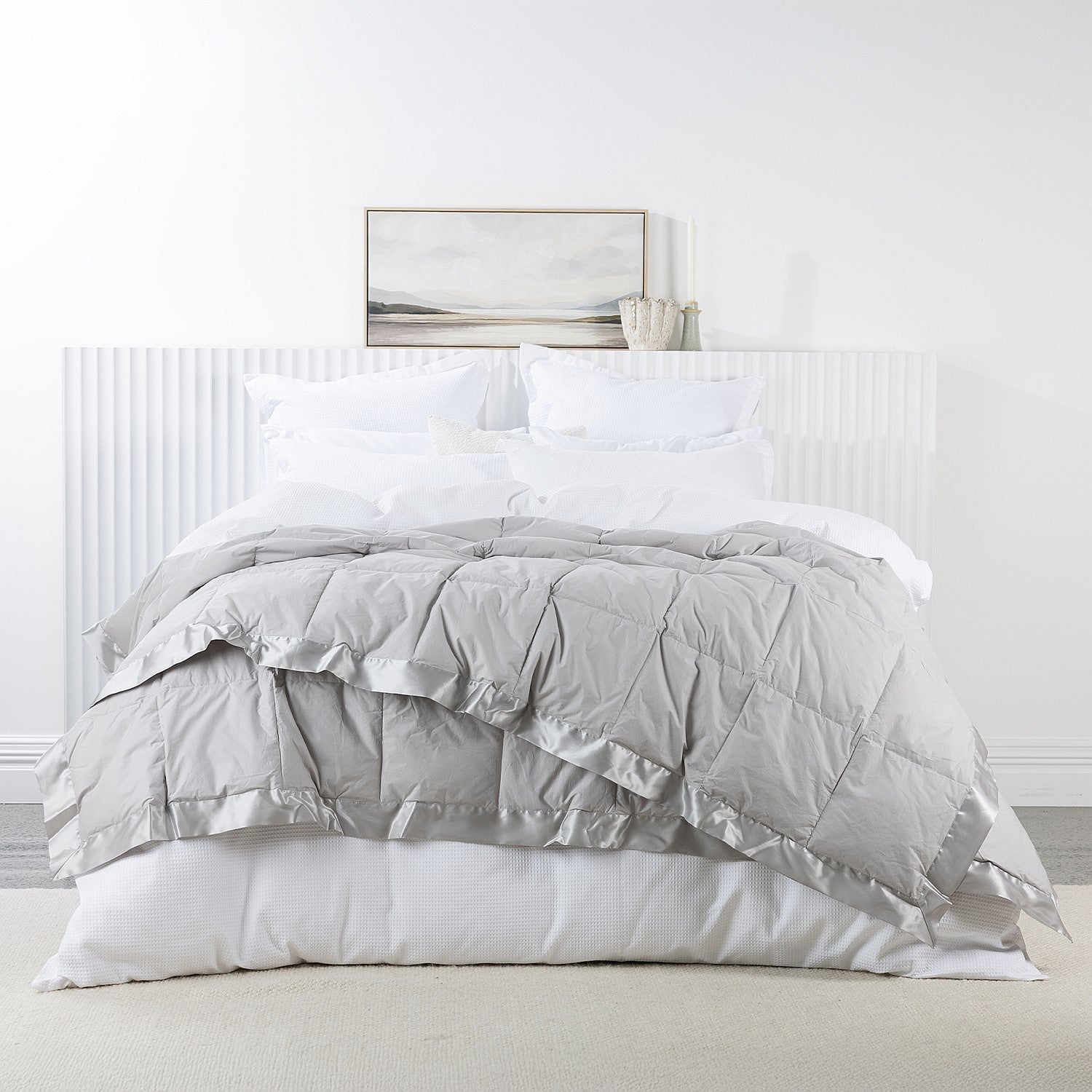 A luxuriously soft feather and down blanket in a light silver-grey tone, finished with elegant satin trim for a calm and sophisticated bedroom look.