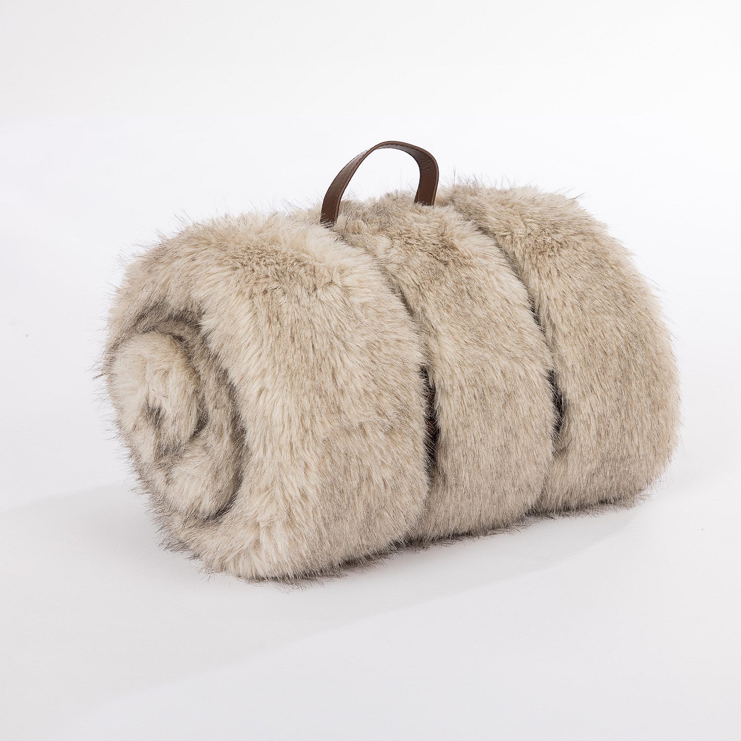 A luxuriously soft rolled faux-fur blanket in a warm oat tone, finished with a rich brown leather carry handle for a refined, cozy look.