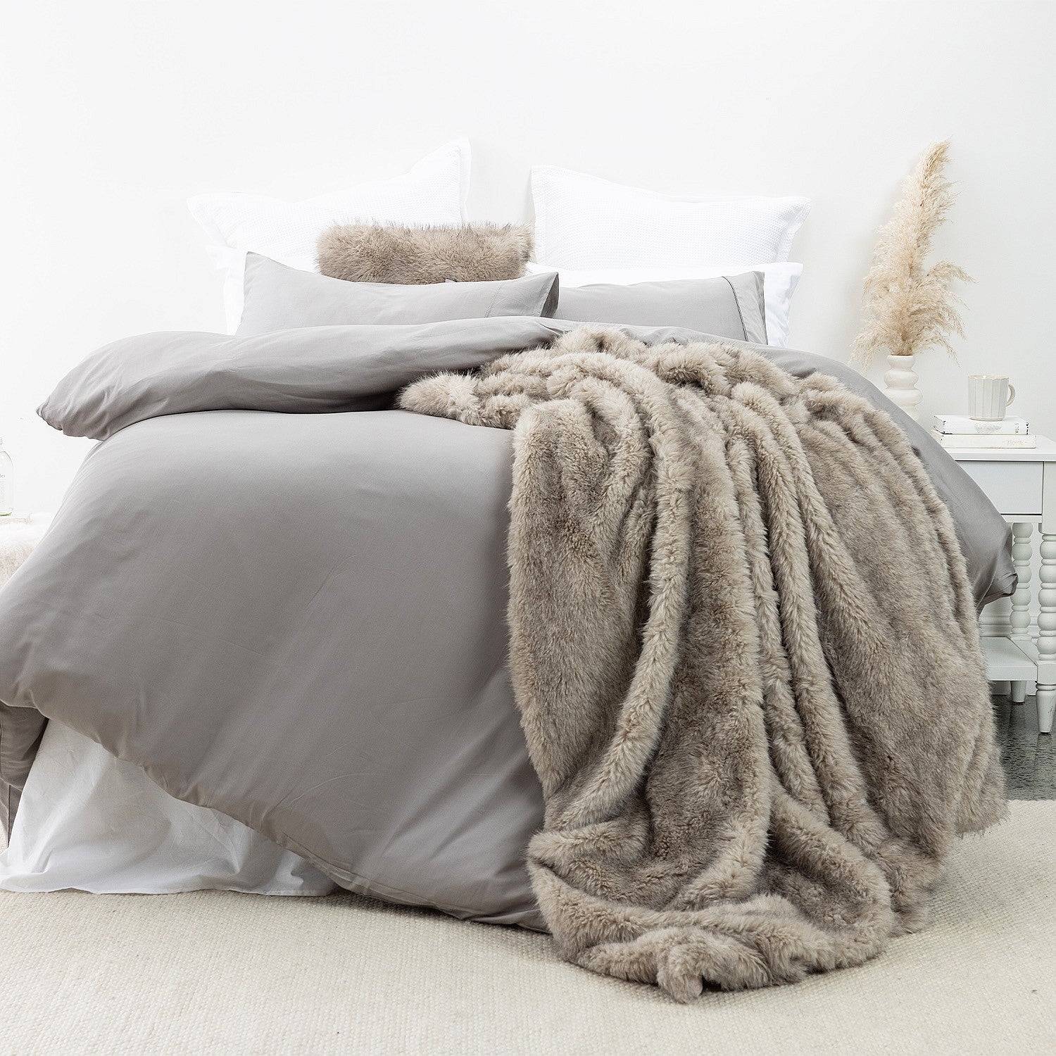 An ultra-plush faux-fur blanket in soft taupe tones, designed to drape beautifully across the bed with rich texture and cozy warmth.