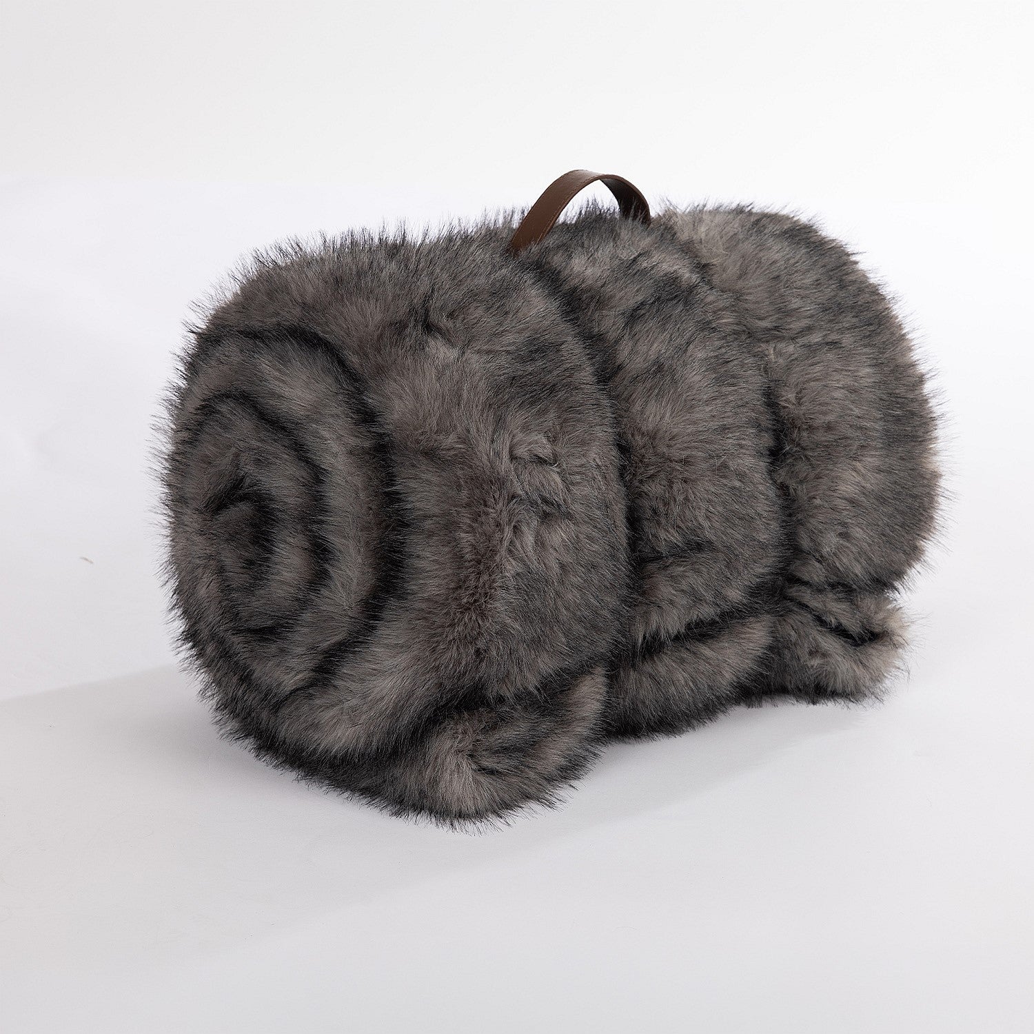 A luxuriously soft charcoal faux-fur throw, neatly rolled and secured with a refined brown leather carry handle for an elevated, cozy finish.