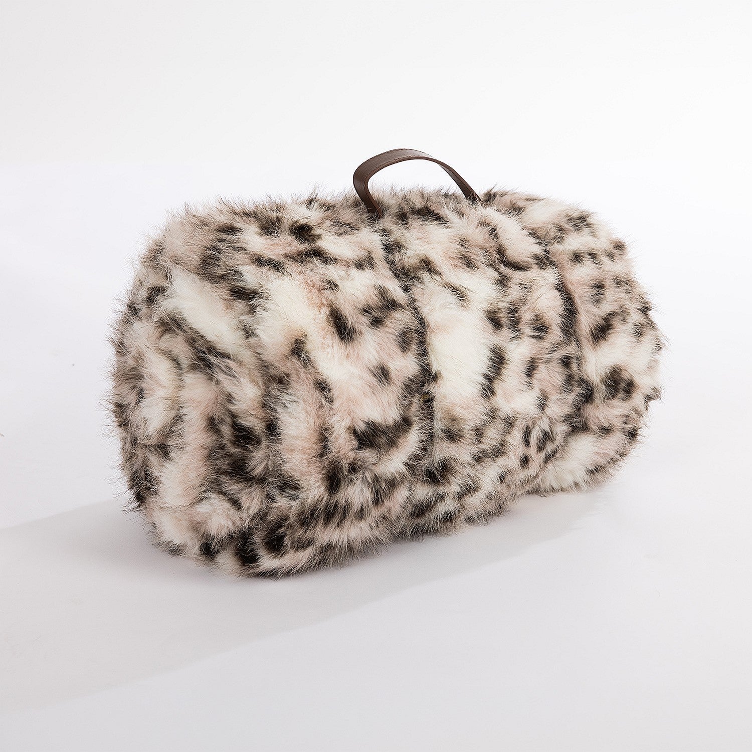 A luxuriously soft snow leopard faux-fur blanket, neatly rolled and finished with a refined brown leather carry handle for a chic, cozy accent.