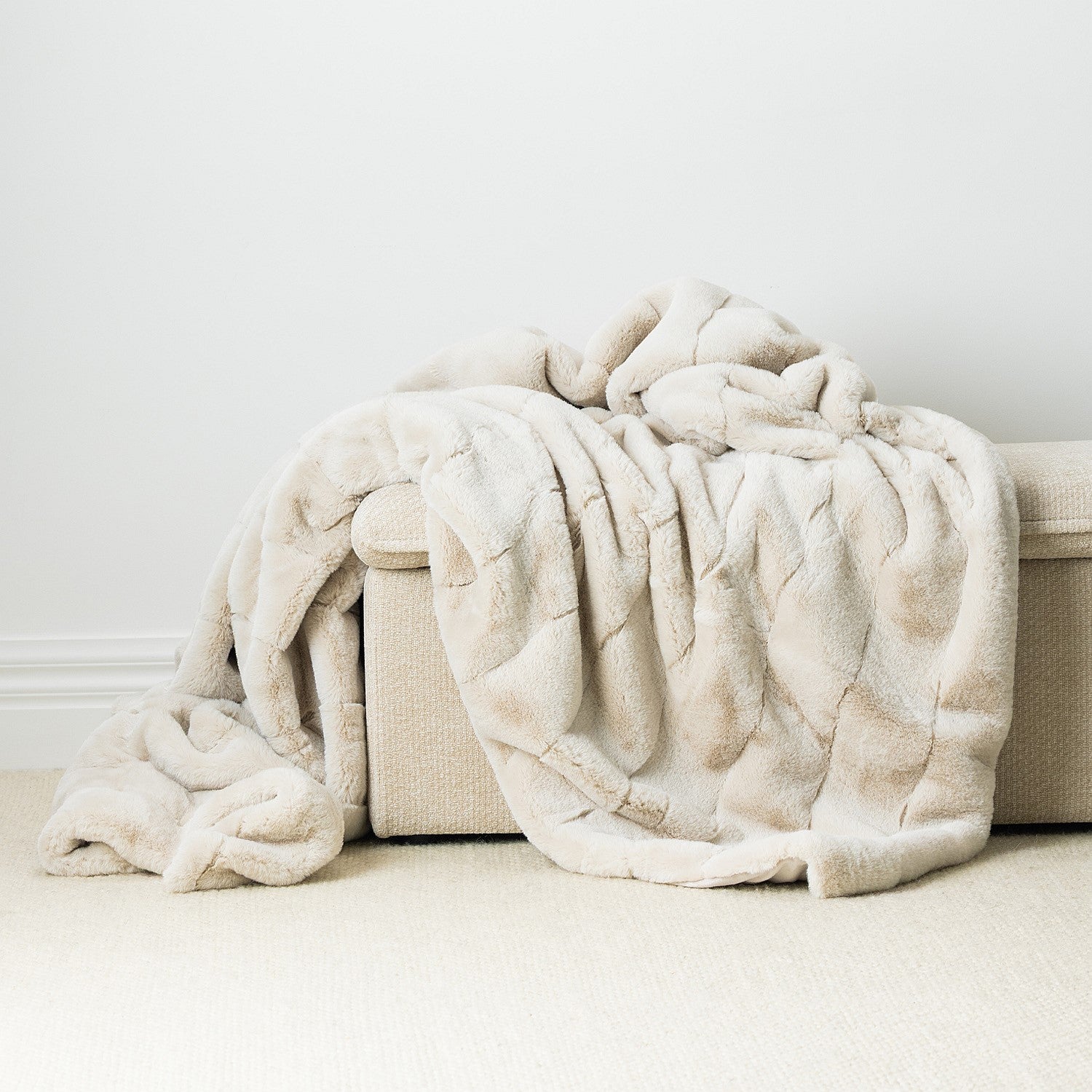 An irresistibly soft faux-fur blanket in a warm ivory hue, featuring subtle tonal patterning and a beautifully plush, cocooning drape.