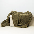 A luxuriously soft olive-toned faux-fur throw with subtle quilted detailing, elegantly draped to showcase its rich texture and cozy warmth.