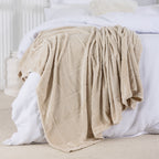 Beige blanket draped over a bed with white bedding