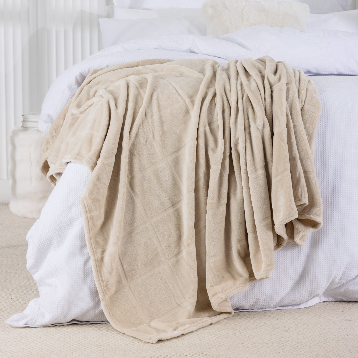 Beige blanket draped over a bed with white bedding