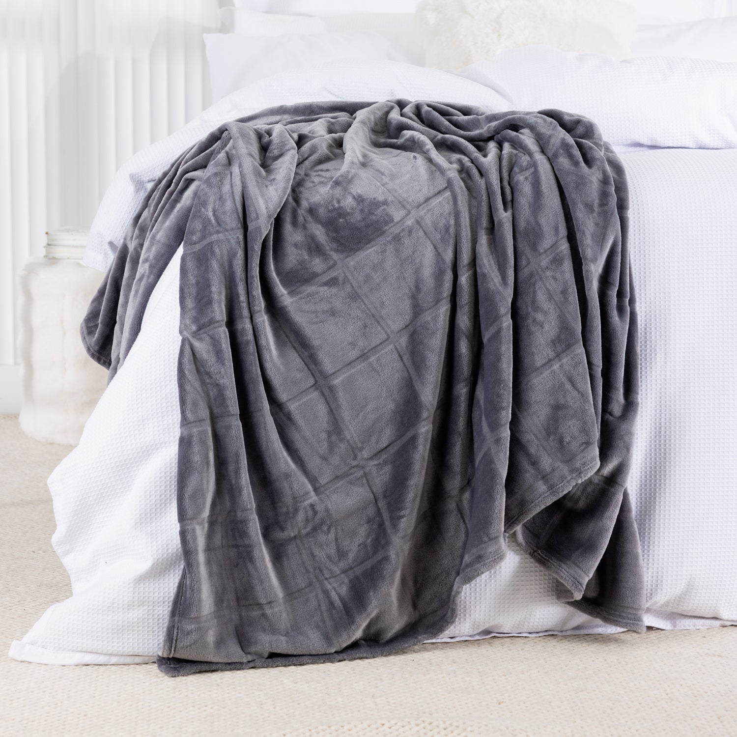 Gray textured blanket draped over a white bed