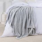 Gray blanket draped over a white bed in a bedroom setting