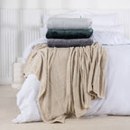 Stack of folded blankets on a bed with a neutral color palette