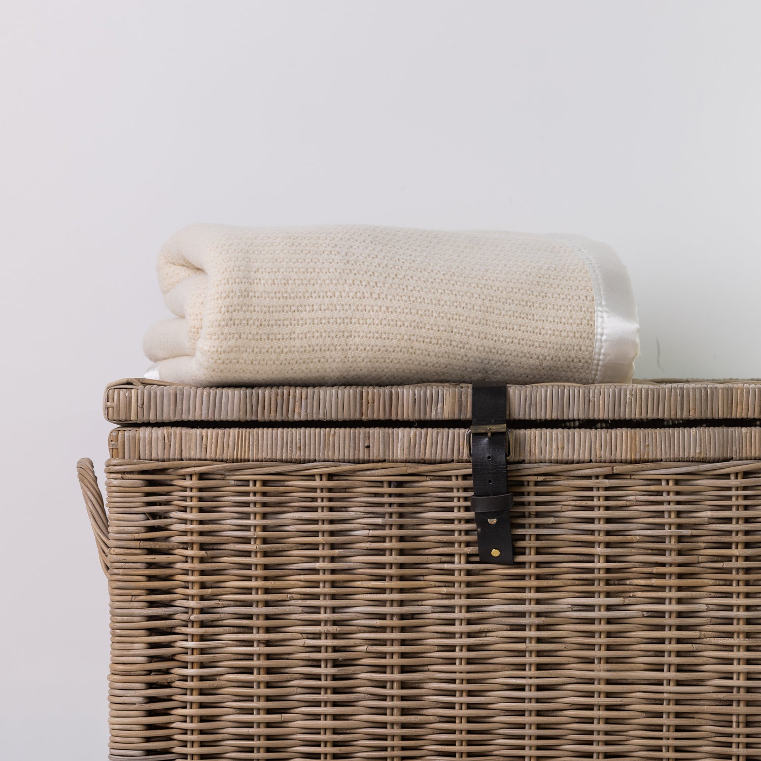 Woolrest Woolcell glacier blanket folded on a wicker basket.