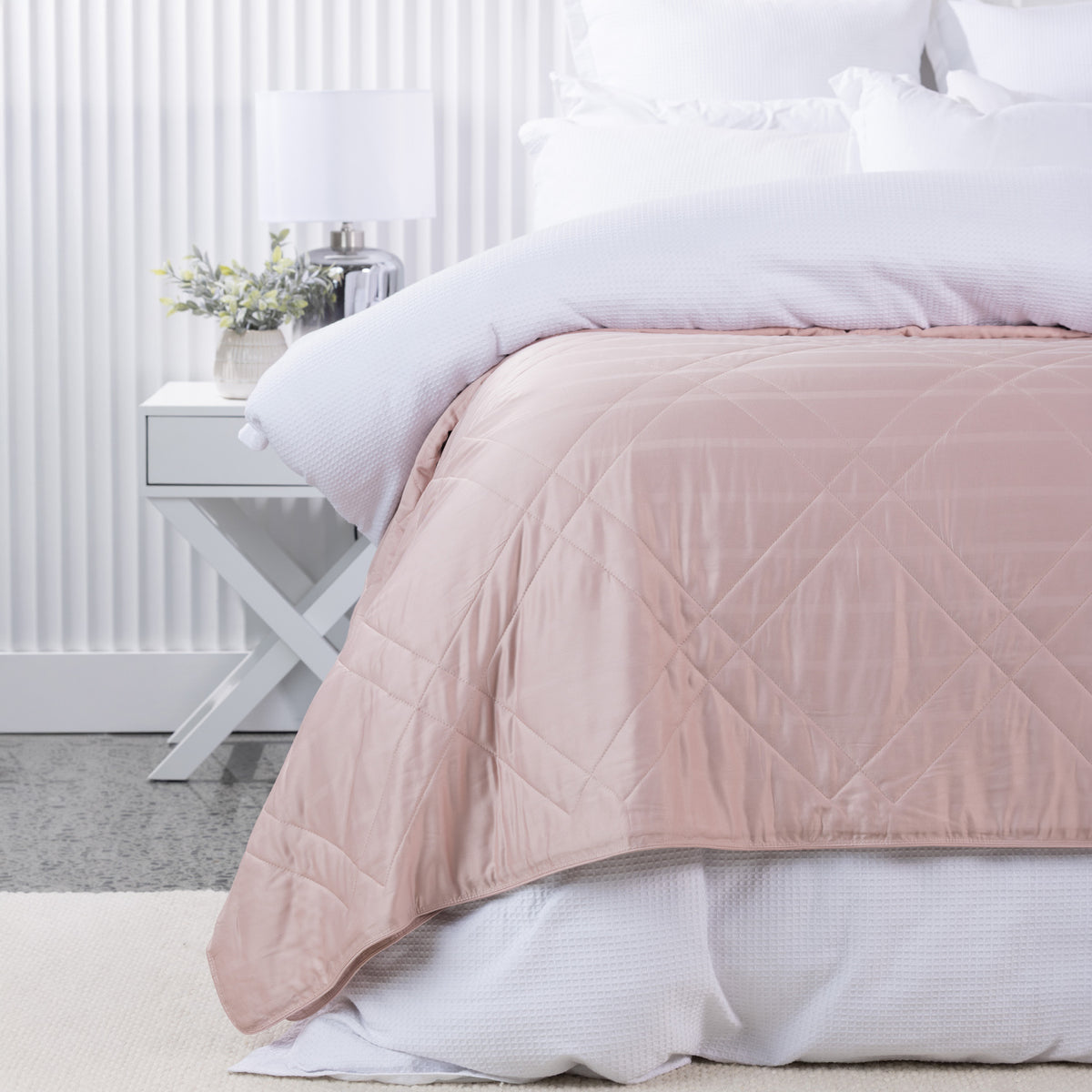 Bambou Summer Blanket in Blush styled on a white bed, featuring a soft pink tone and large diamond quilted pattern.