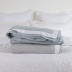 folded blankets on a bed Pebble & Duck egg.
