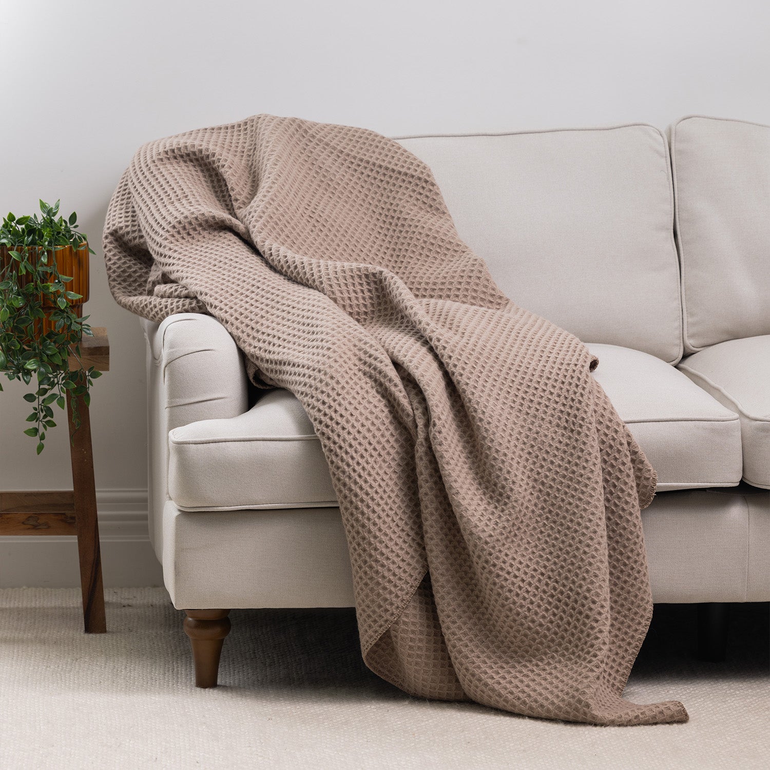 Moonlight waffle weave blanket draped over the arm of a cream sofa, highlighting its soft textured finish in a modern living room.