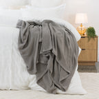 Dove aircell blanket draped across a white bed, featuring a textured waffle weave and plain border.