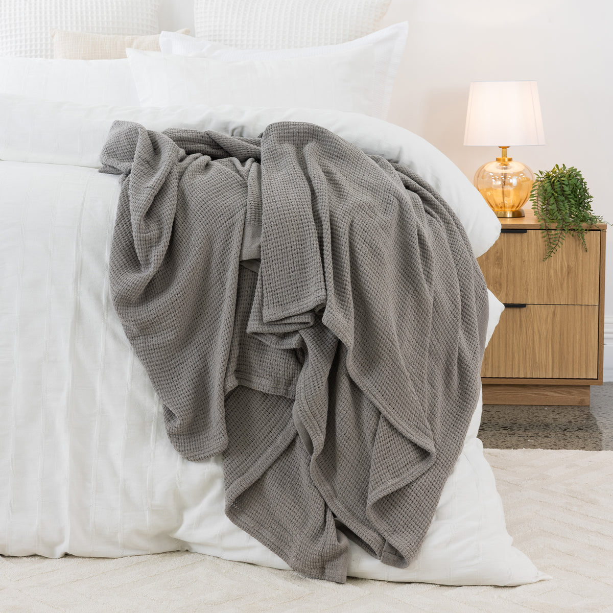 Dove aircell blanket draped across a white bed, featuring a textured waffle weave and plain border.