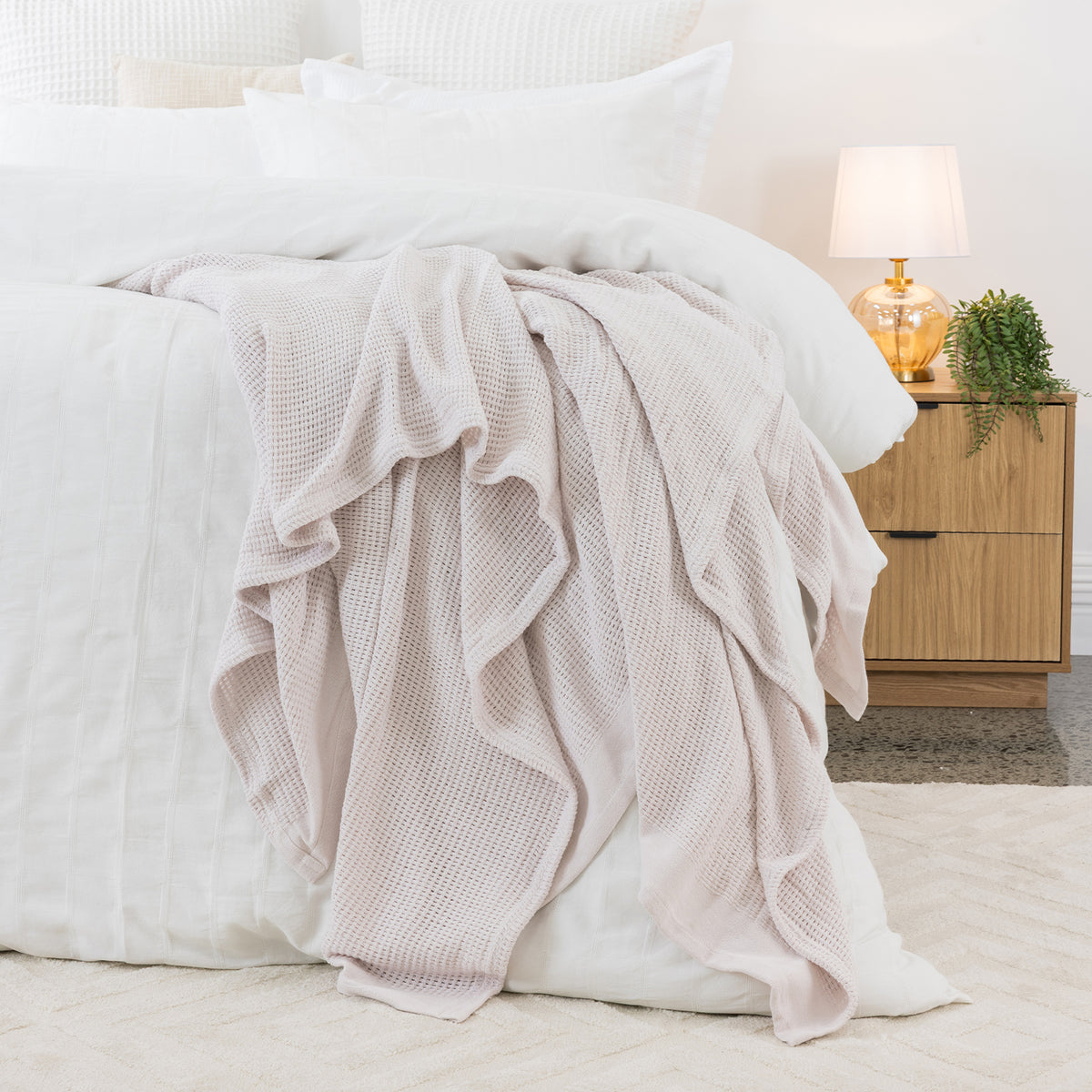 Linen aircell blanket draped across a white bed, featuring a textured waffle weave and plain border.