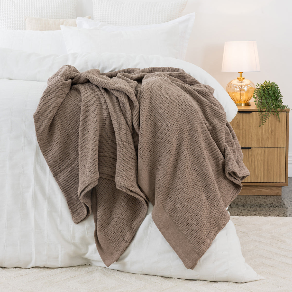 Mocha aircell blanket draped across a white bed, featuring a textured waffle weave and plain border.