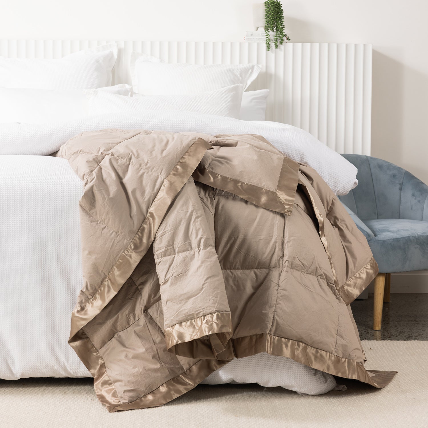 Fieldcrest duck down blanket in Driftwood, draped over the end of a white bed to showcase the soft quilted design with satin trim.