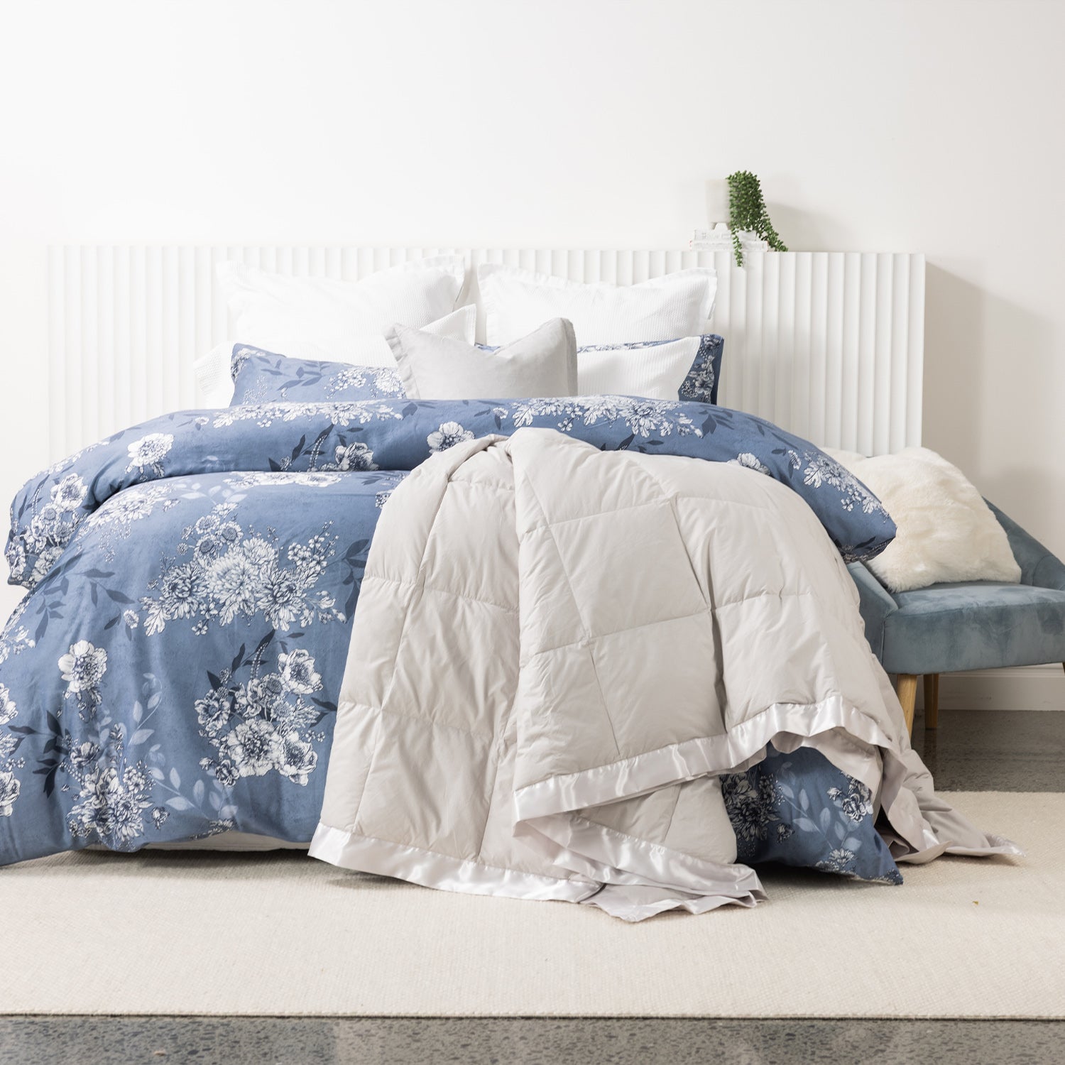 Fieldcrest duck down blanket in Pumice, draped over the end of a white bed to showcase the soft quilted design with satin trim.