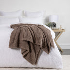 Driftwood Solace Trellis Blanket draped across a white bed, showing its soft textured trellis pattern in a neutral brown tone.