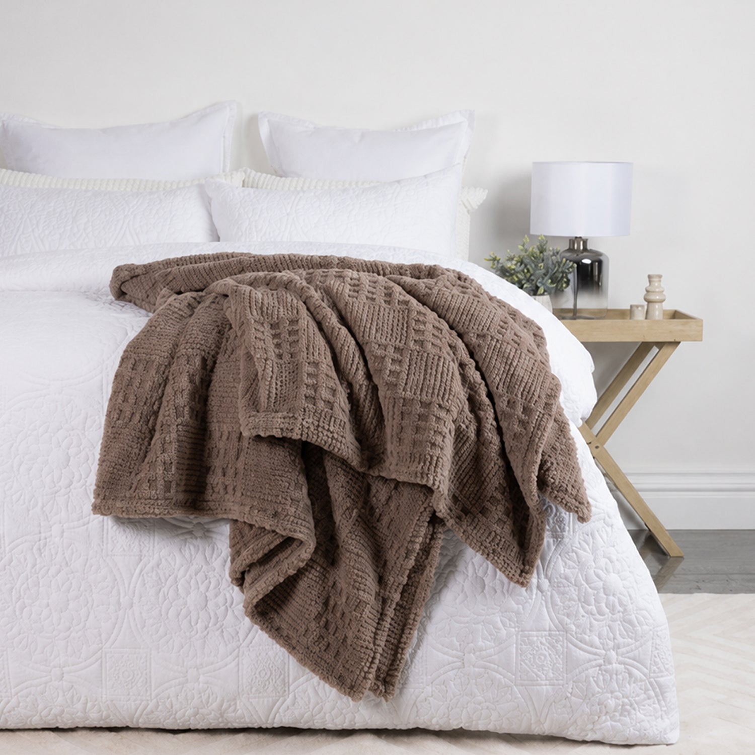 Driftwood Solace Trellis Blanket draped across a white bed, showing its soft textured trellis pattern in a neutral brown tone.
