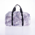 A fluffy faux-fur duffel bag in a lavender-gray tie-dye pattern with black handles, photographed on a clean white background.