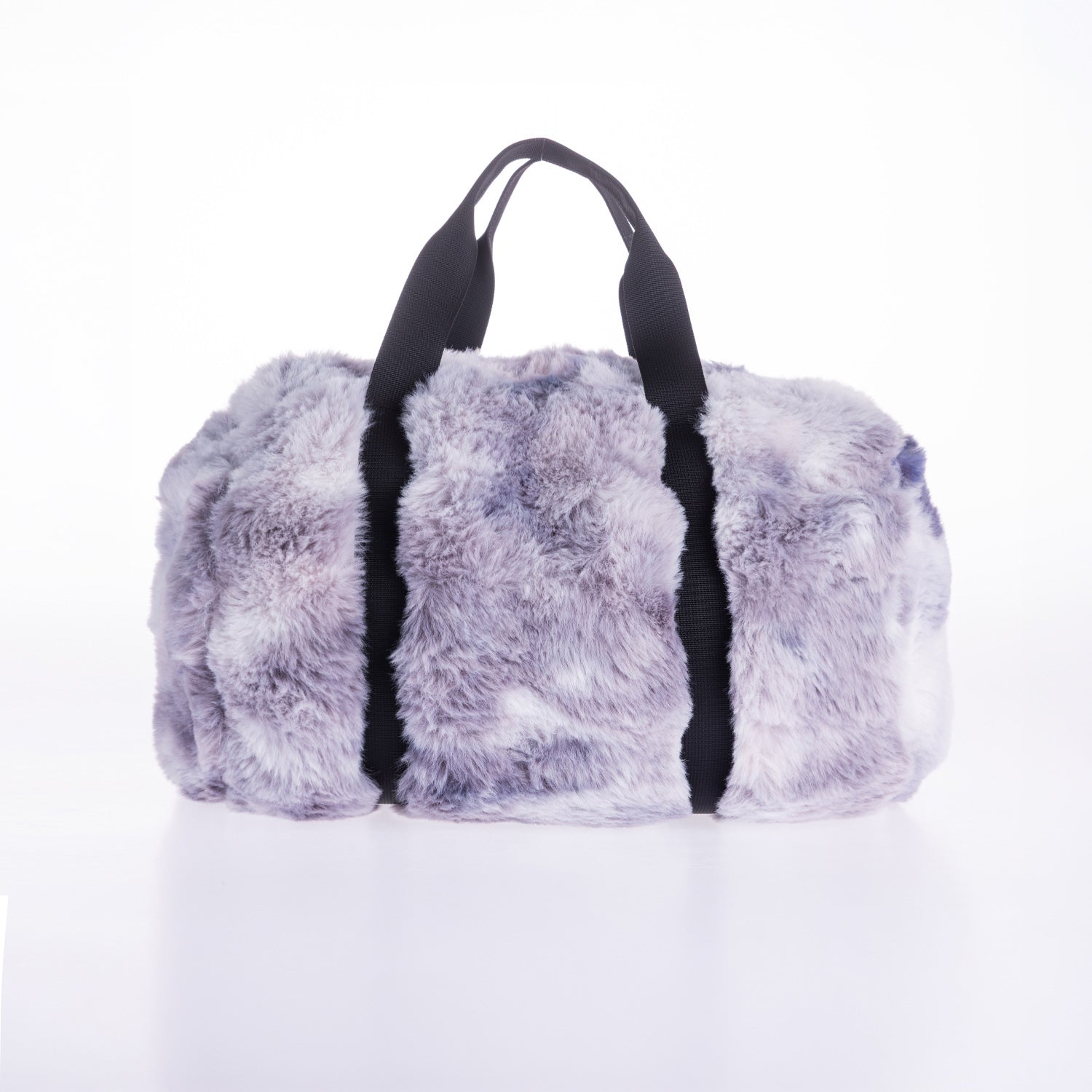 A fluffy faux-fur duffel bag in a lavender-gray tie-dye pattern with black handles, photographed on a clean white background.
