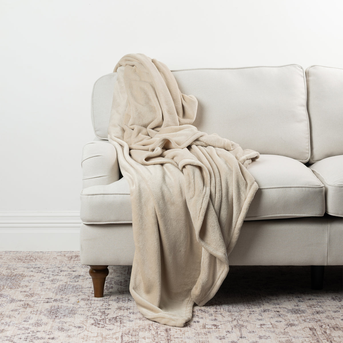 Champagne Home Co. Super Plush Blanket draped over a neutral sofa, showing its soft plush texture and cosy finish.