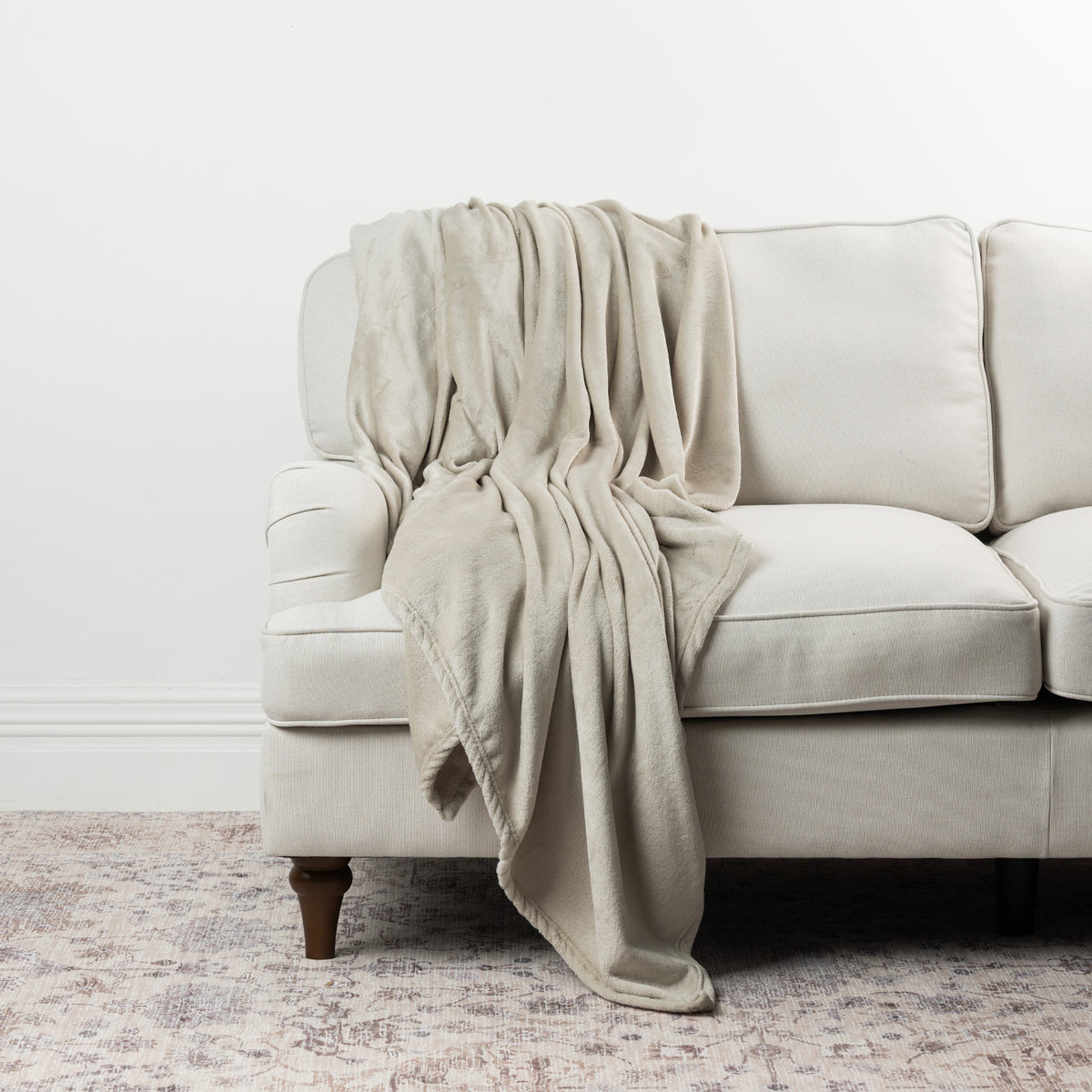 Natural Home Co. Super Plush Blanket draped over a neutral sofa, featuring a soft plush texture and neutral tone.