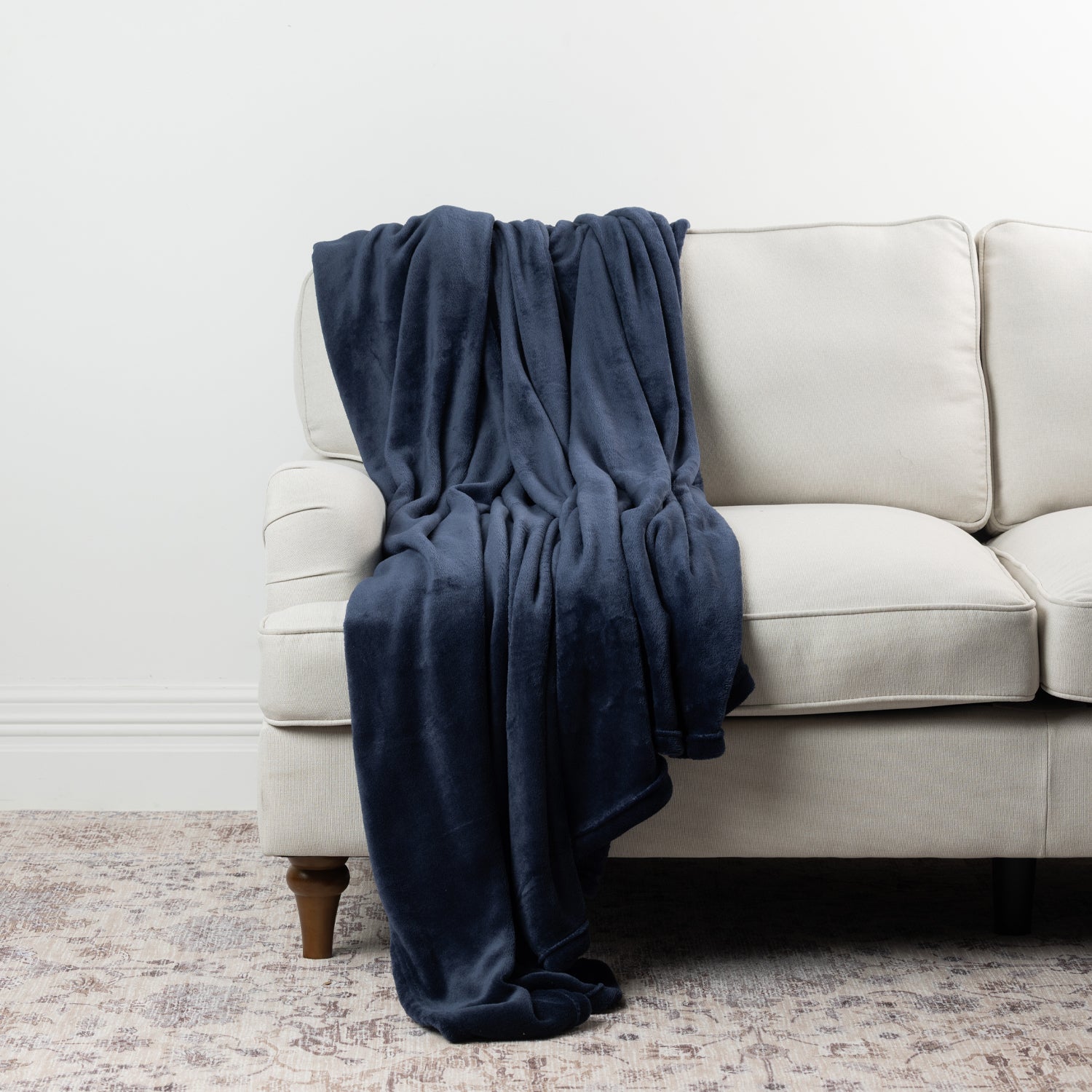 Navy Home Co. Super Plush Blanket styled over a neutral sofa, showing its deep navy colour and plush finish.